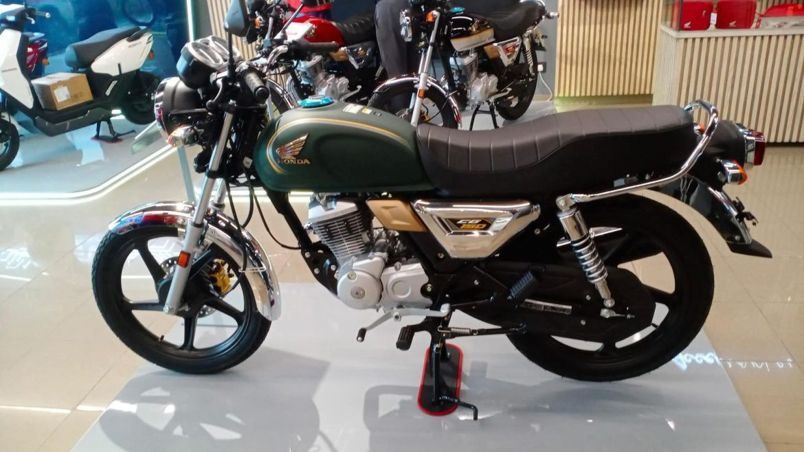 A stylish Honda CG 150 motorcycle in green and black, showcasing chrome accents and a retro design, displayed in a modern showroom.