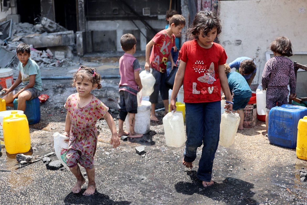 Children carry water containers amidst debris and dirt, showcasing resilience in a challenging environment.