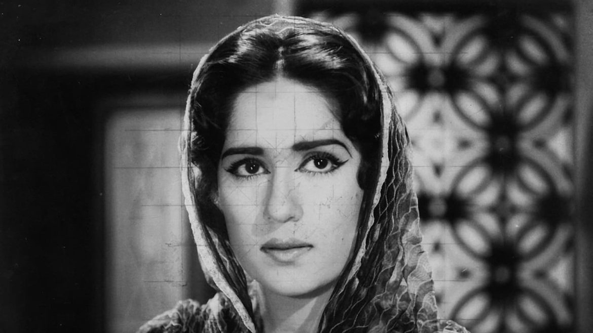 Legendary Pakistani actress and director Shamim Ara in traditional attire, draped in a patterned scarf, stands against a patterned background in a monochrome image.