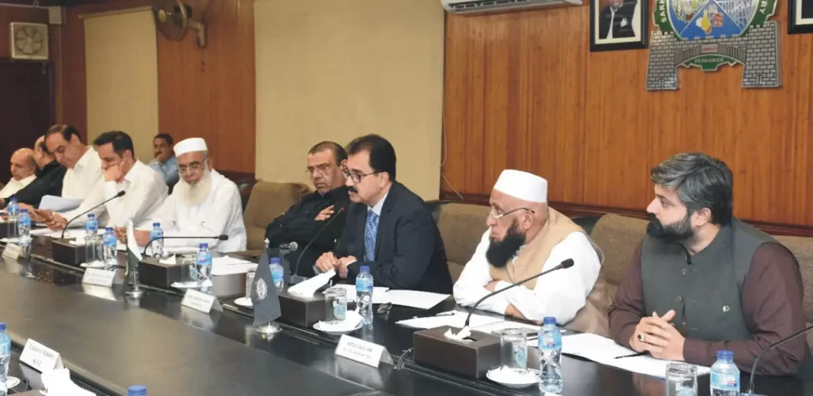 A group of individuals seated around a conference table, engaged in discussion during an official meeting, with documents and water bottles present.