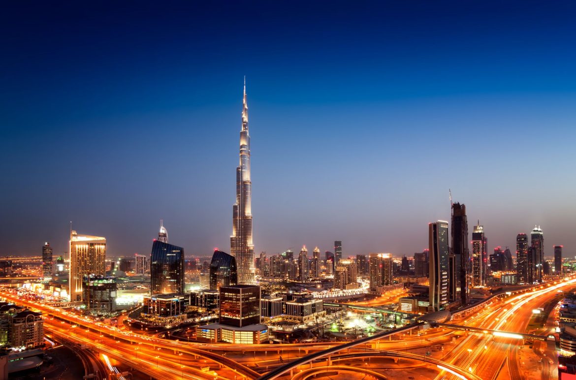 Stunning night skyline of Dubai featuring the Burj Khalifa, bustling highways, and illuminated cityscape against a twilight sky.