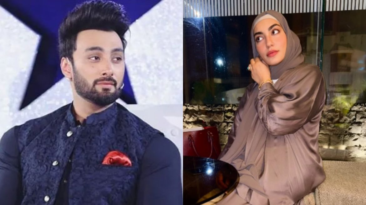 A stylish man in a navy blue outfit sits in a well-lit setting, while a woman in a brown hijab poses beside him, showcasing elegance.