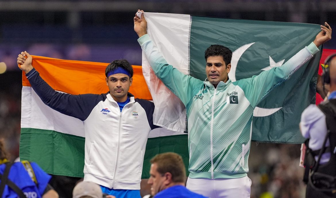 Two athletes celebrate their achievements, holding the Indian and Pakistani flags high in a display of sportsmanship and unity.