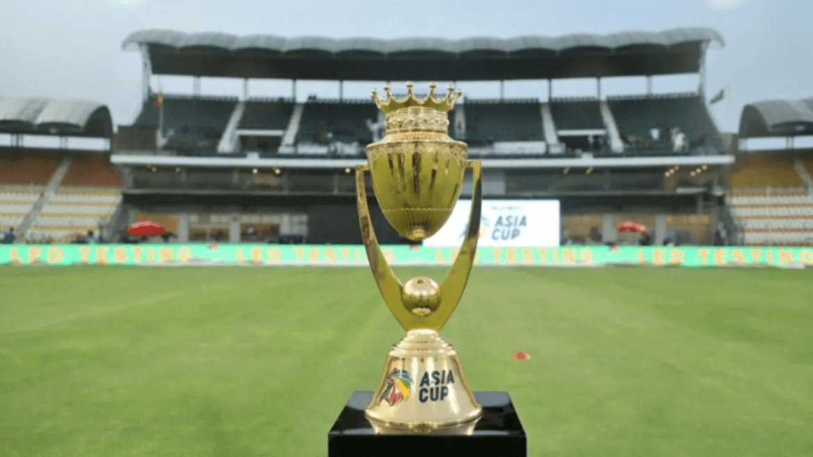 The Asia Cup trophy is displayed on the field with empty stadium seats and LED banners in the background, hinting at a match event.