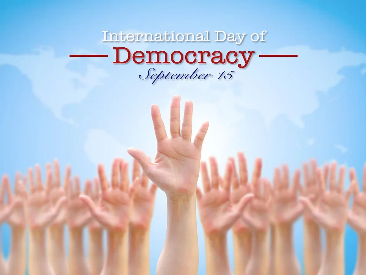 Hands raised in unity against a blue background, celebrating the International Day of Democracy on September 15.