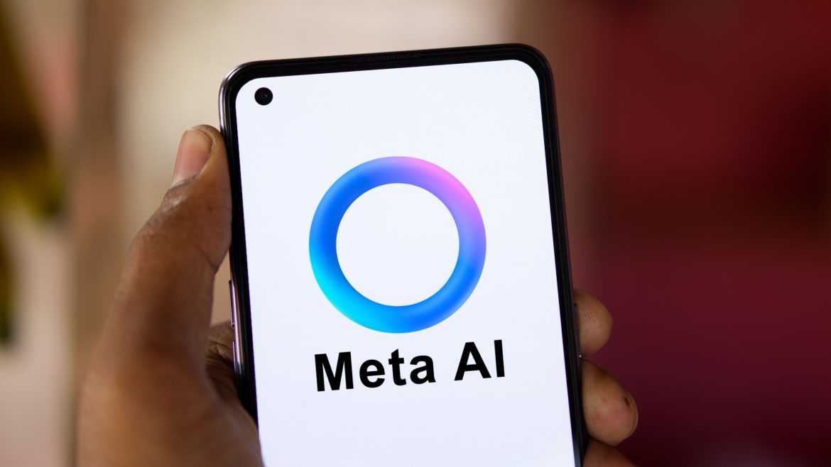 The image shows a smartphone held in a hand displaying the Meta AI logo, featuring a colorful circular design with the text "Meta AI" beneath it.