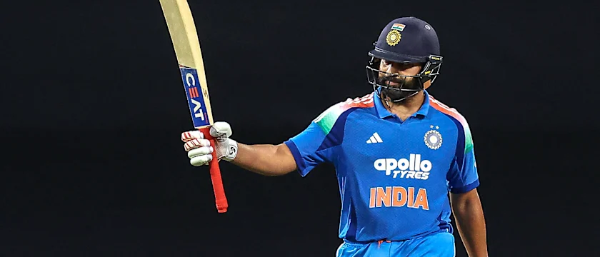 An Indian cricketer in a blue jersey celebrating with a bat raised high, showcasing team spirit and enthusiasm during a match.