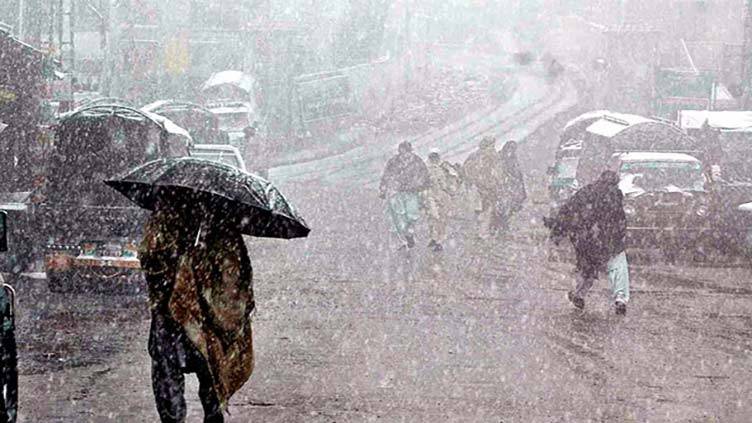 Heavy snowfall blankets a busy street, with pedestrians navigating the storm under umbrellas while vehicles are partially obscured by snow.