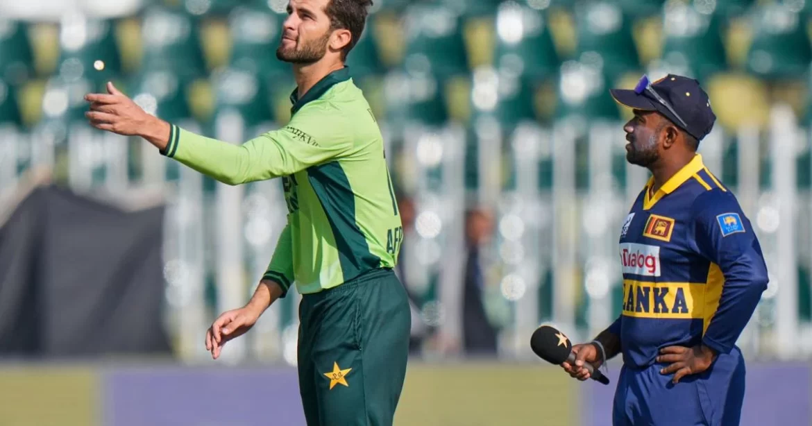 A Pakistani cricketer in a green uniform gestures during a match, while a Sri Lankan player in a blue uniform observes nearby.