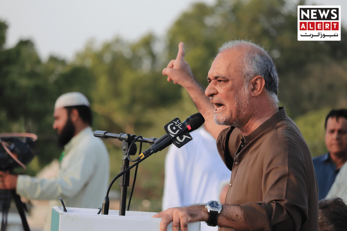 A speaker gestures passionately at a podium during an outdoor event, with audience members and cameras in the background.