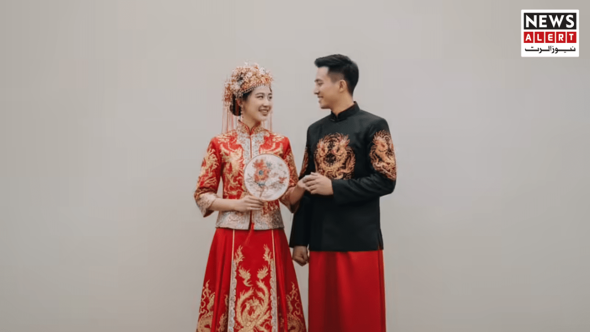 A couple in traditional Chinese wedding attire, the woman in a red dress with gold embroidery, holding a decorative fan.