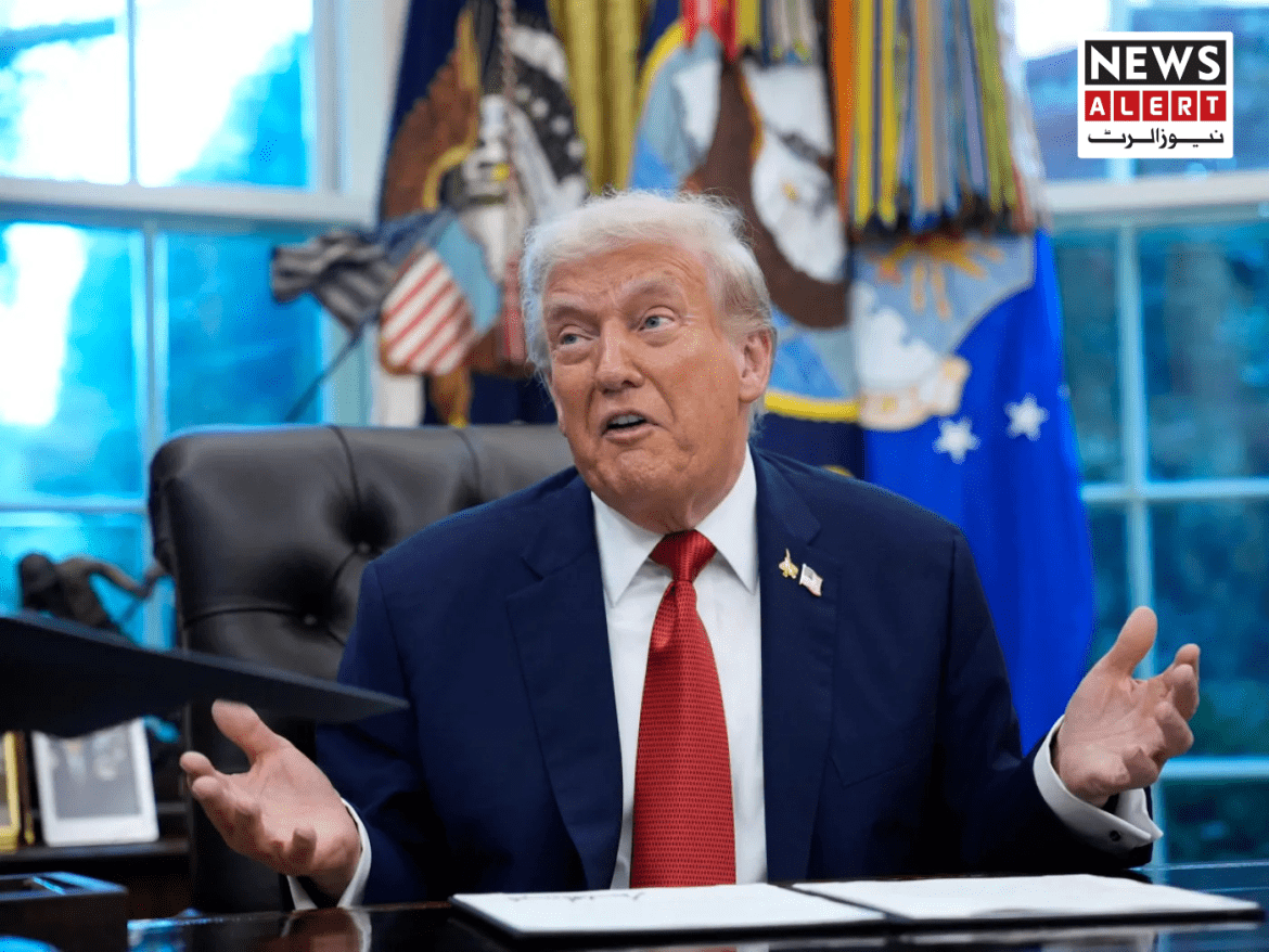 A person in a suit gestures while seated at a desk in a well-decorated office, with flags and official seals in the background.