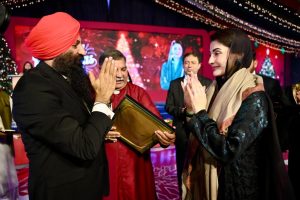 A group of elegantly dressed individuals engaged in conversation, with festive decorations in the background, creating a vibrant atmosphere.